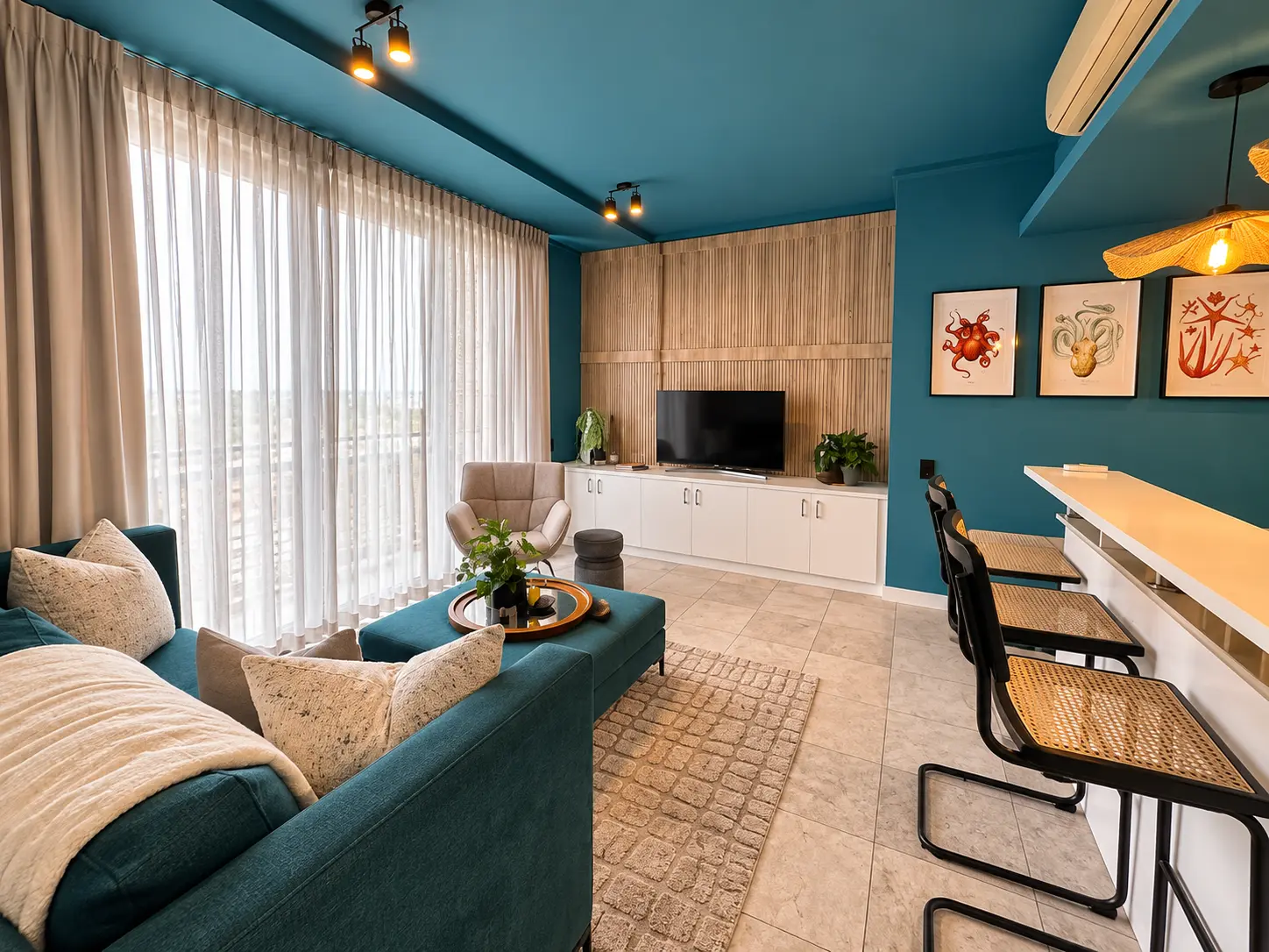 Teal open-plan lounge with floor-to-ceiling windows and breakfast bar