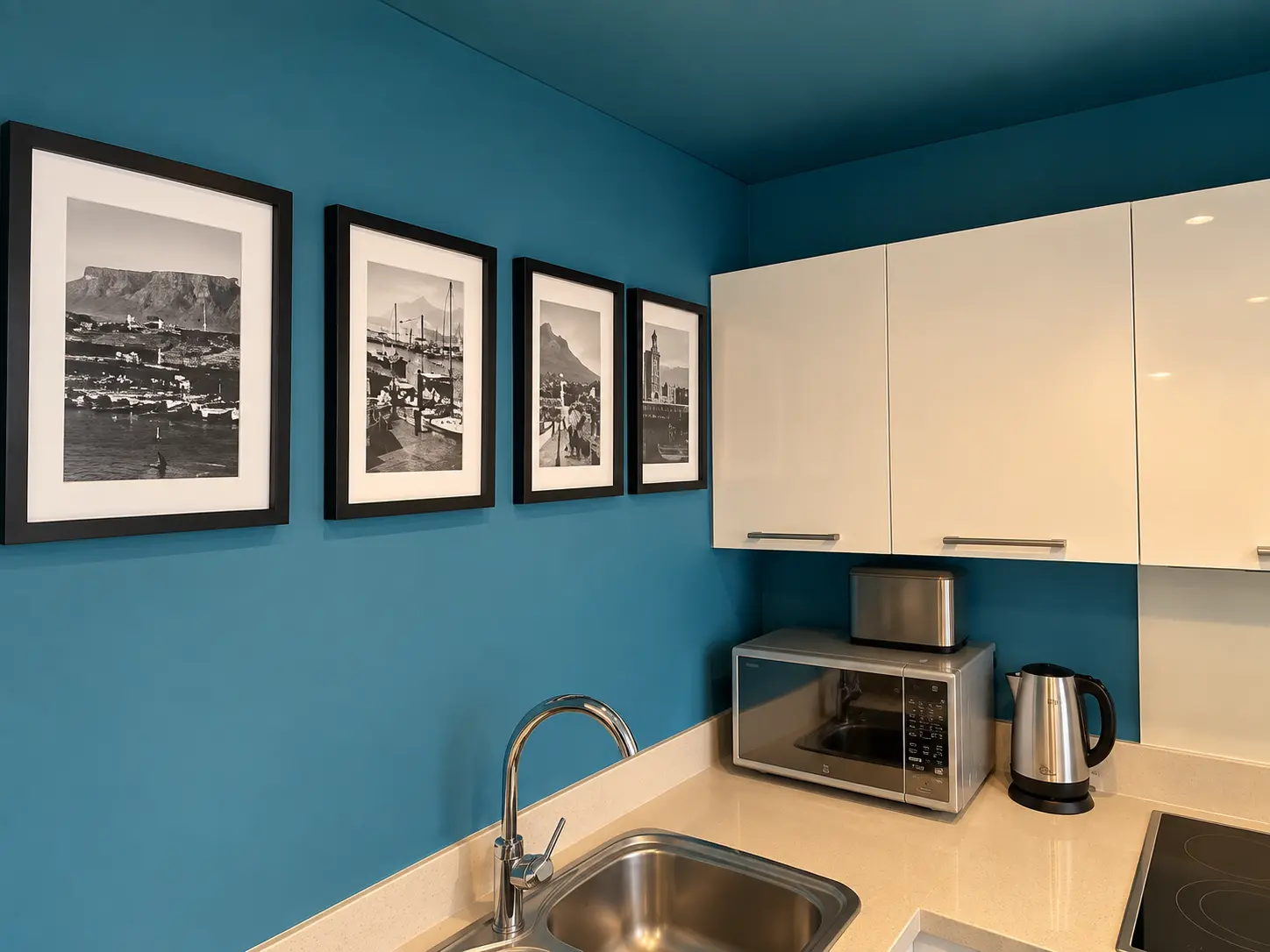 Teal kitchen wall with Cape Town artwork and appliances